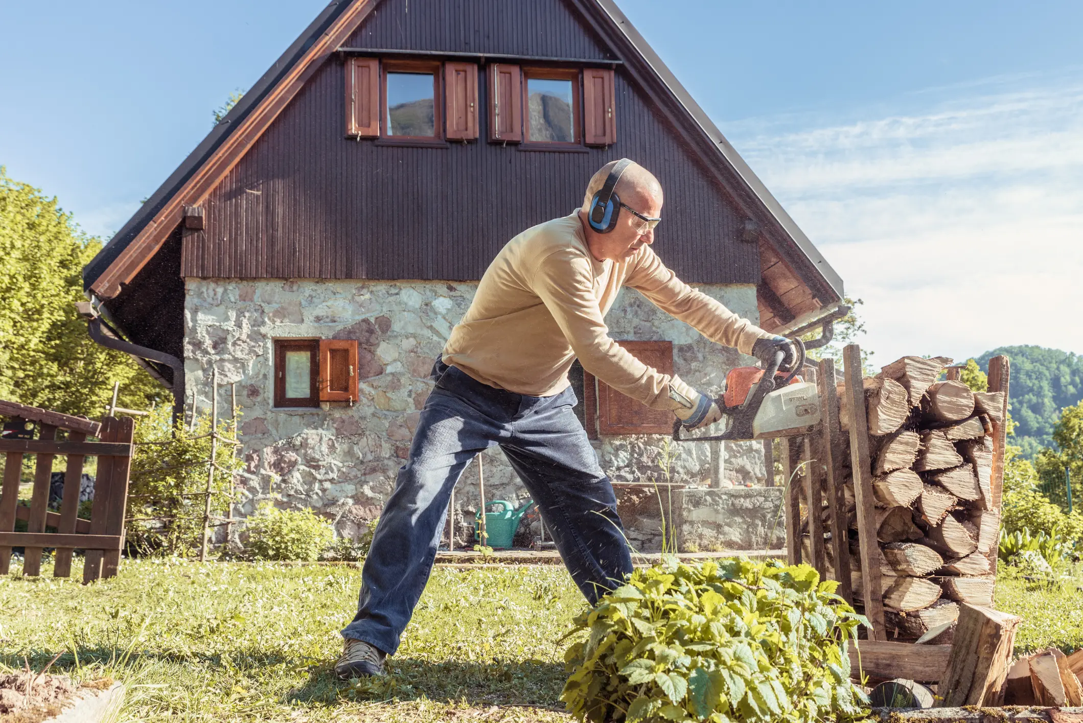 Man Cutting Firewood for the Heating Season Using Chainsaw